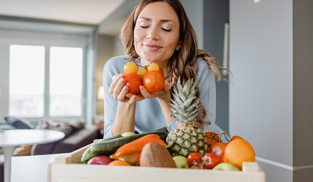 young woman holding fresh produce in kitchen at Dylan Point Loma Apartment